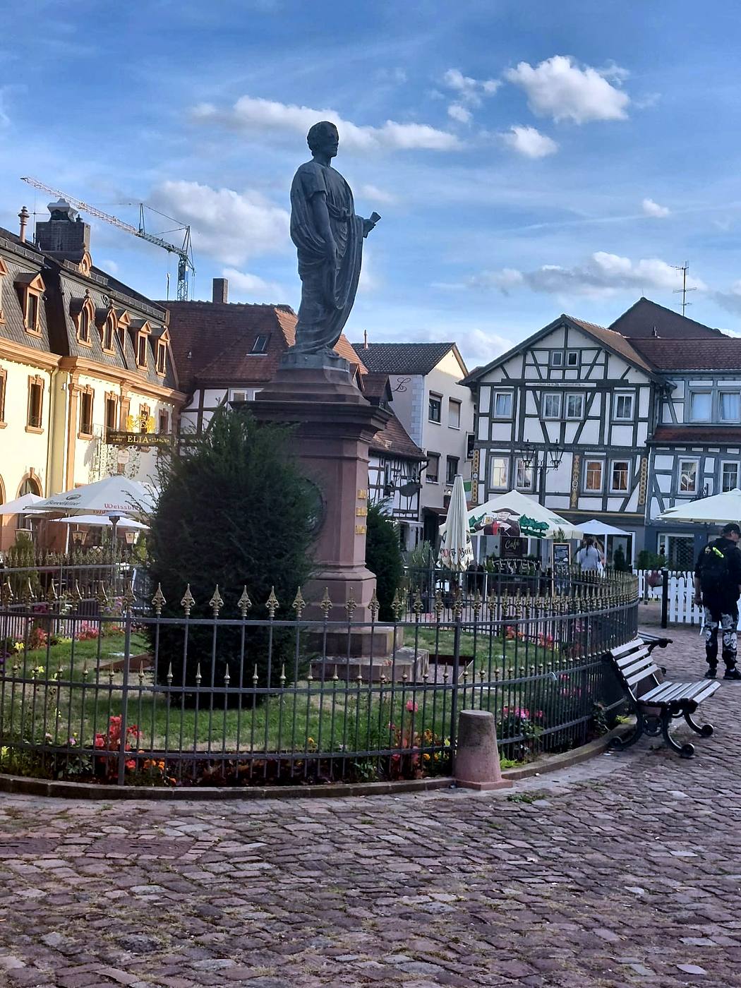 Standbild des Grafen Franz I. zu Erbach-Erbach in römischer Toga auf rotem Sandsteinsockel am Marktplatz Erbach, dahinter Fachwerkhäuser und Cafés