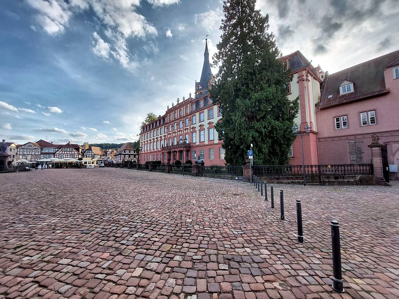 Weiter Schlossplatz in Erbach im Odenwald mit Kopfsteinpflaster, der Front von Schloss Erbach und Fachwerkhäusern mit Cafés