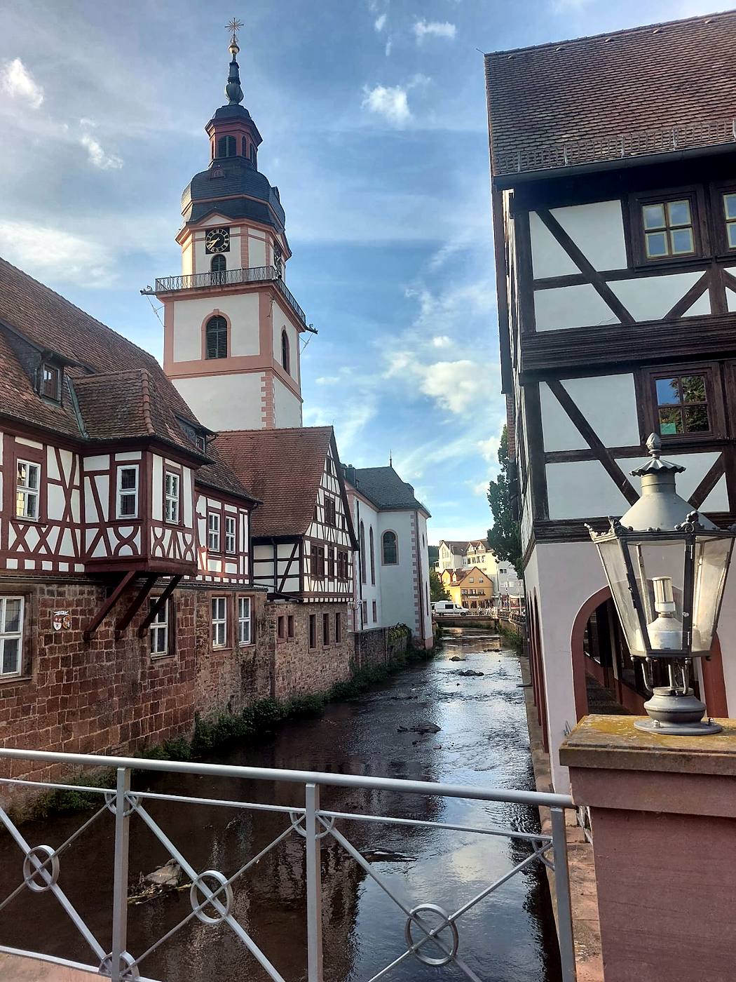 Blick von der Brücke in Erbach auf Fachwerkhäuser mit Erker direkt an der Mümling und den Turm der evangelischen Stadtkirche